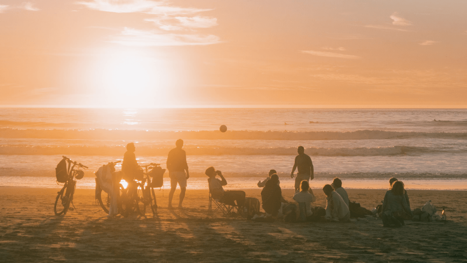 Picnic setup with a low table, cushions and flowers on the beach at sunset near Marbella